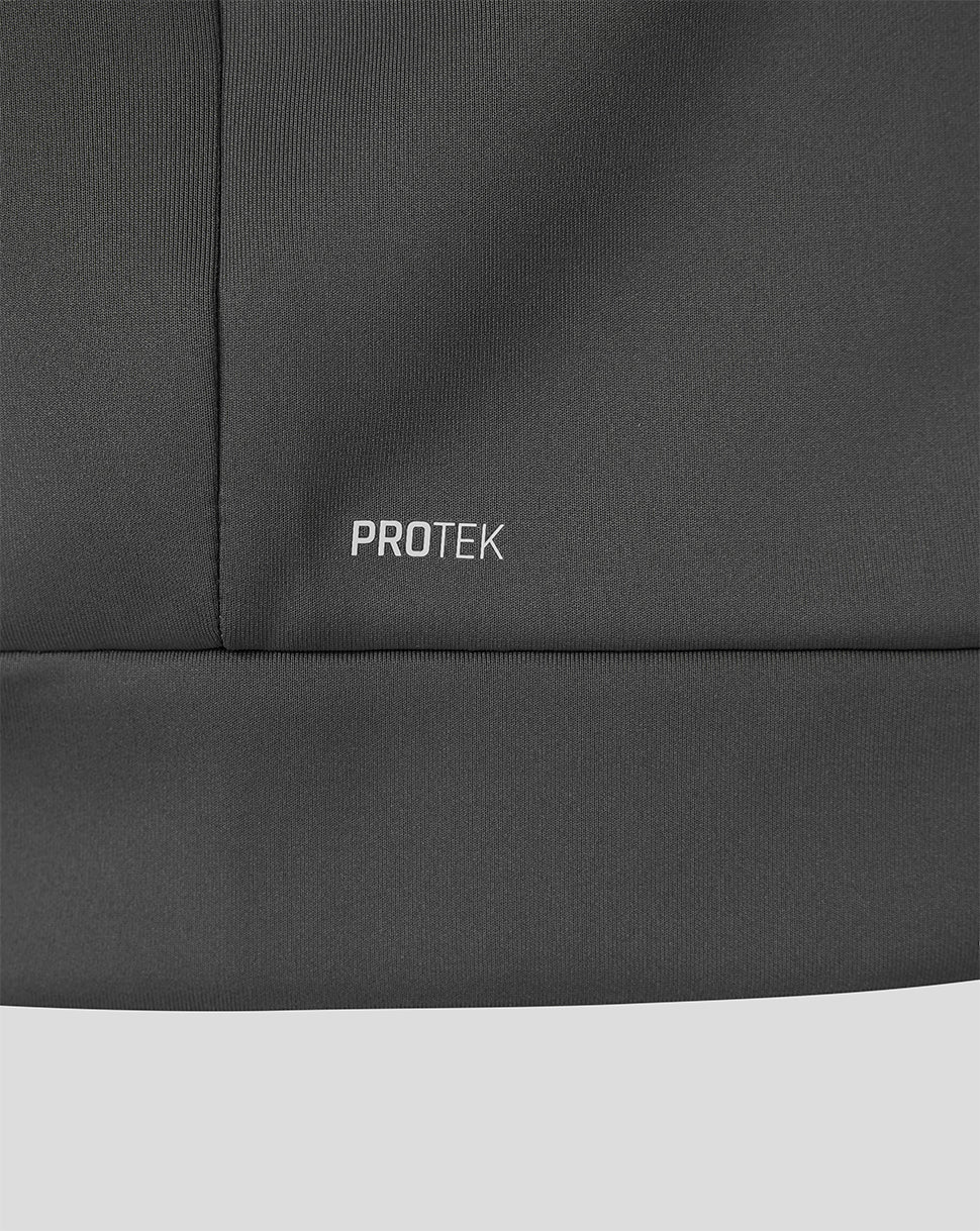 Close-up of a dark gray athletic jacket showing the 'PROTEK' logo embroidered on the chest, with a light gray background visible at the bottom.