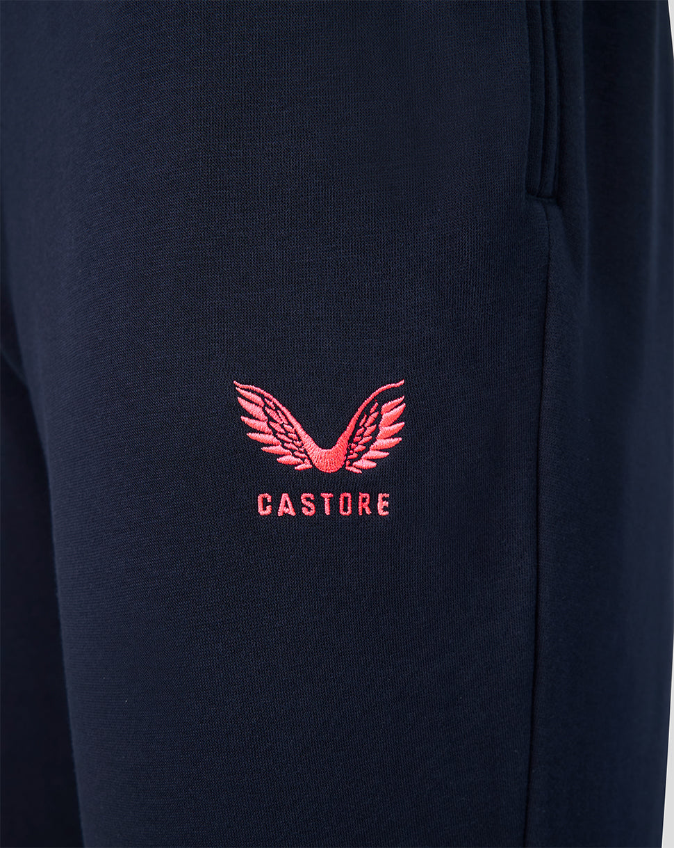 Close up of navy travel joggers showing a pink embroidered Castore logo on the leg