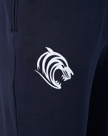 Close up of navy travel joggers fabric with a white embroidered tiger logo on the leg.