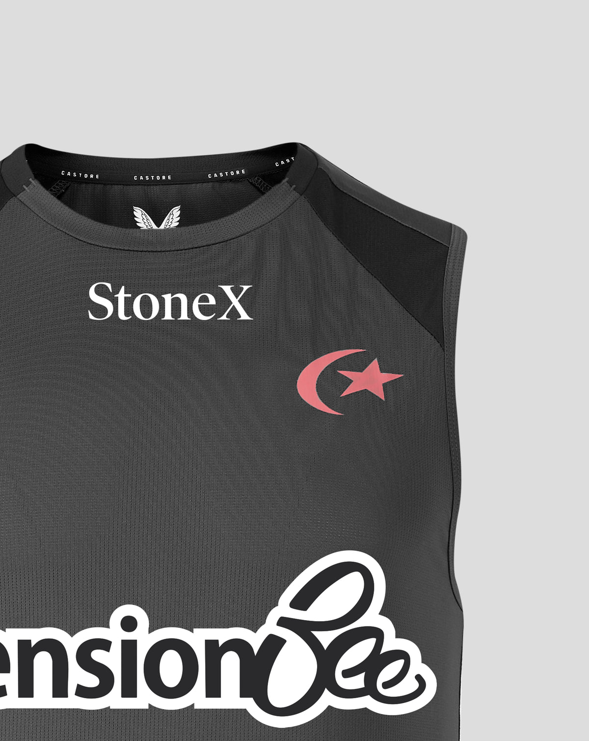 Close-up of a sleeveless dark gray athletic top with black shoulder panels, featuring the StoneX logo in white on the chest and a pink crescent and star graphic. The bottom shows part of a large white script logo.