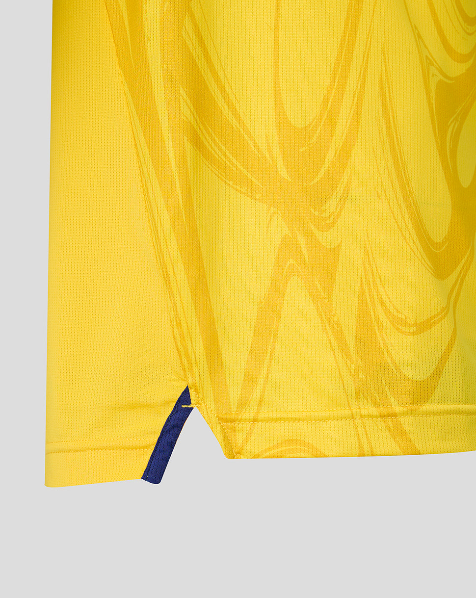 Close-up of yellow shirt hem showing a small blue vent at the side