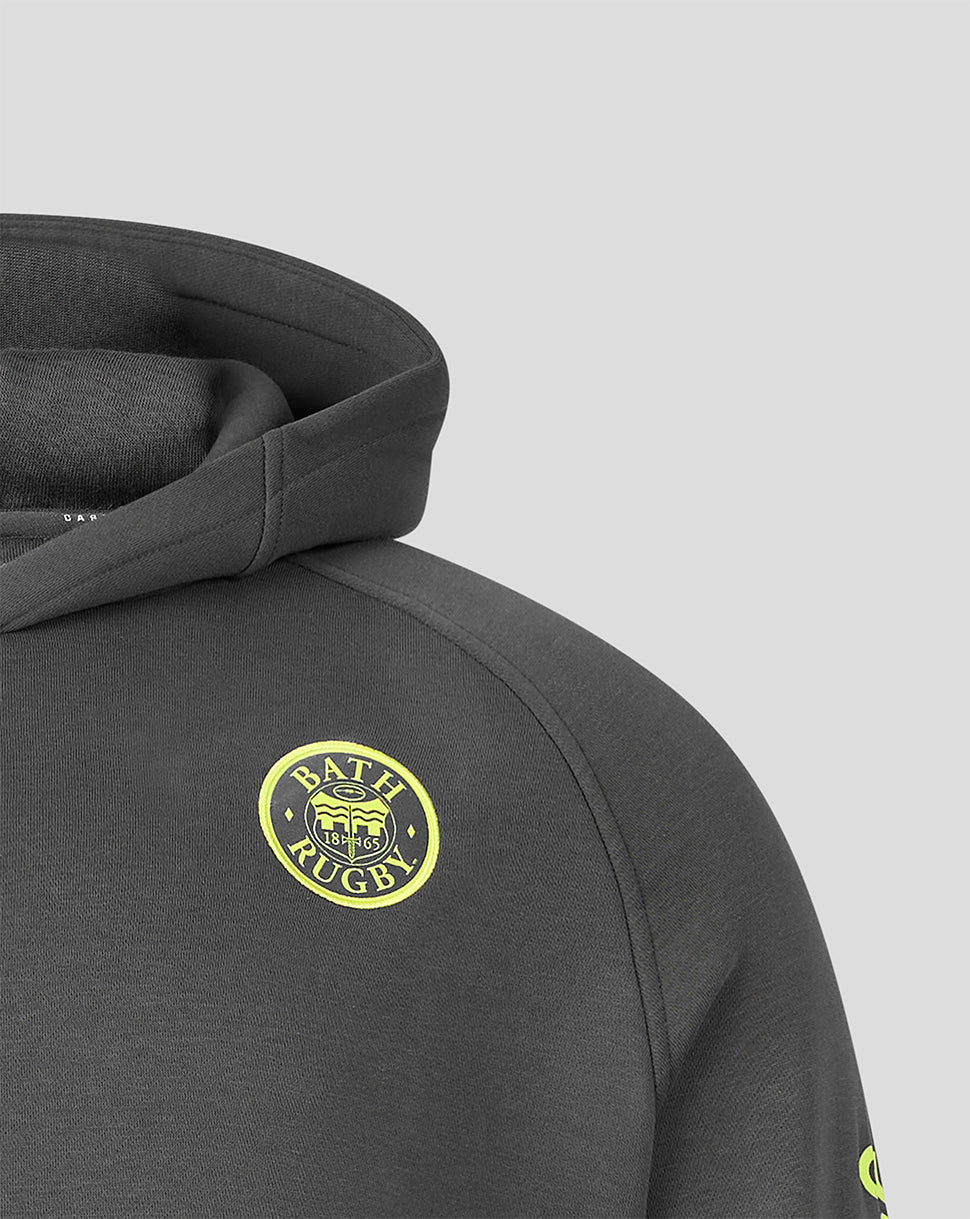 Close-up of a dark gray heathered hoodie featuring a circular yellow and black 'BATH RUGBY' crest patch on the chest, set against a solid light gray background.