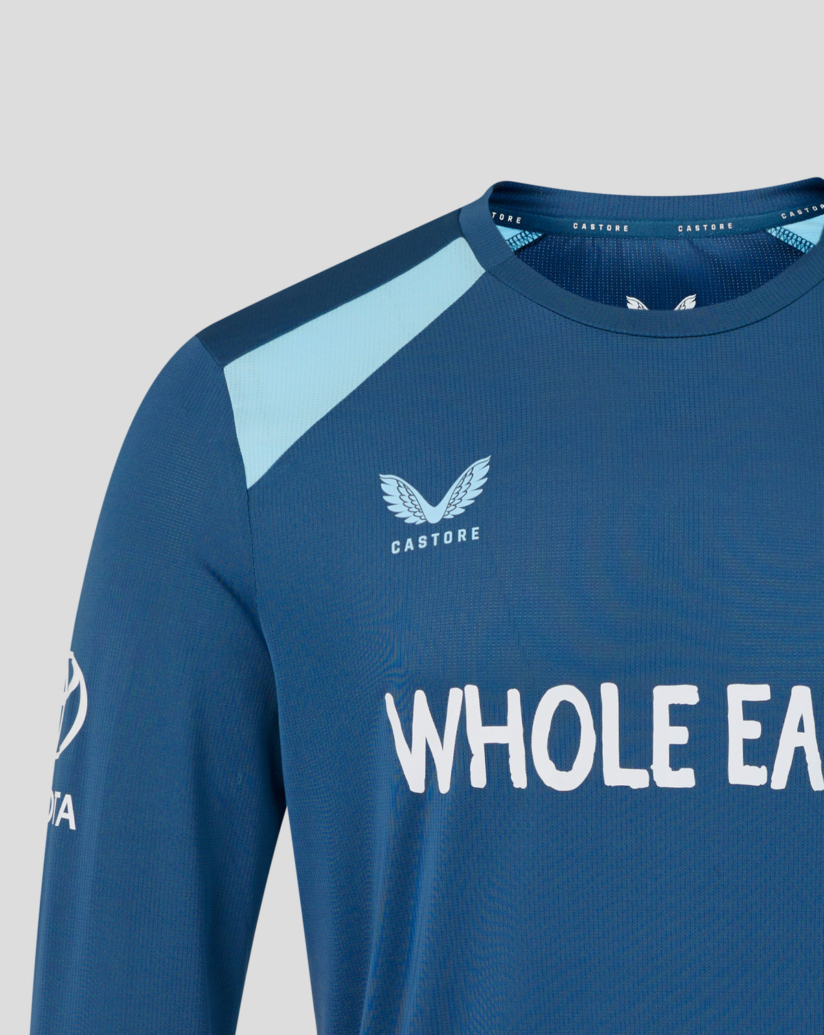 Blue athletic shirt with 'Castore' logo and text on a light gray background