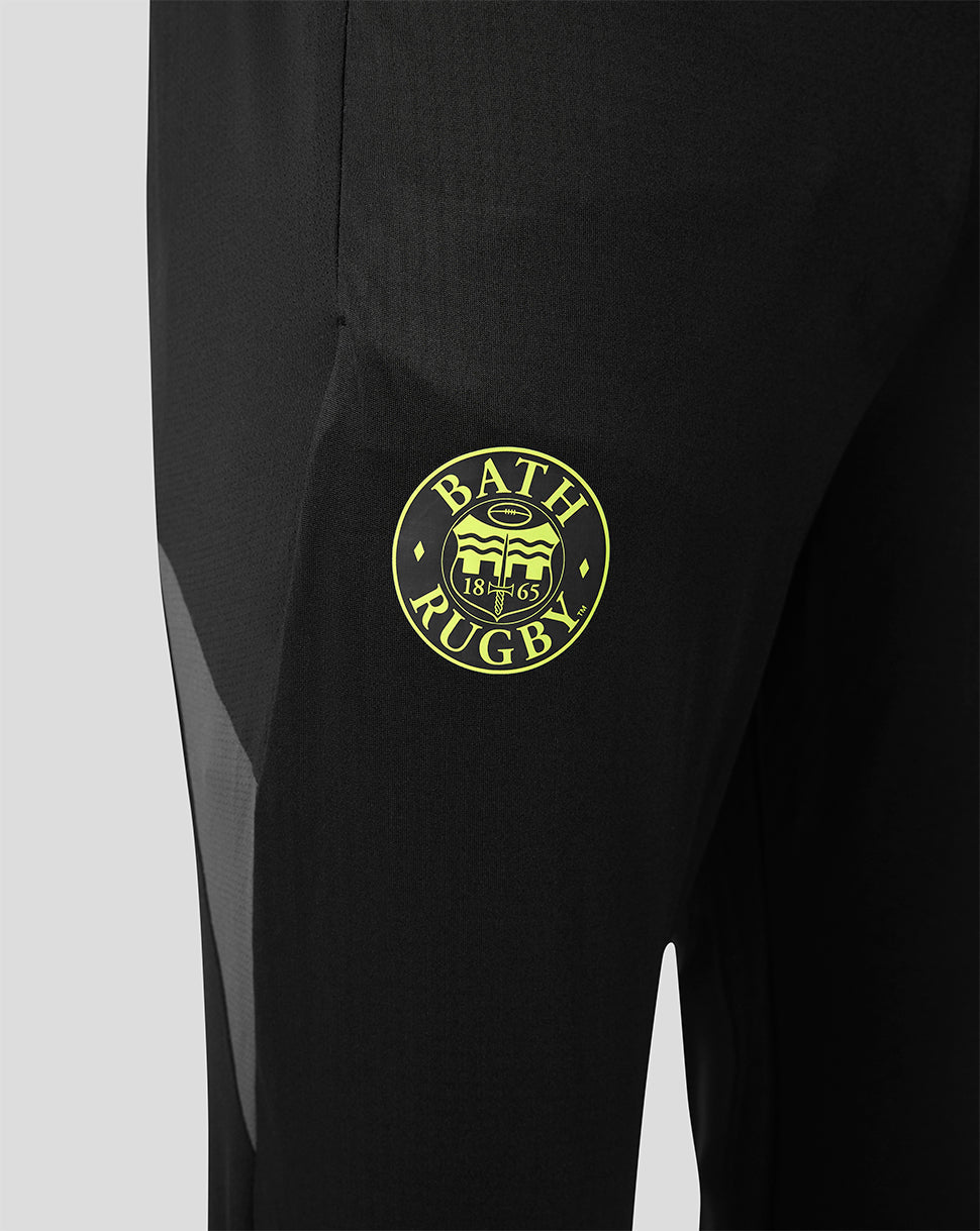 Close-up of black athletic pants with a circular yellow-green Bath Rugby crest patch on the thigh.