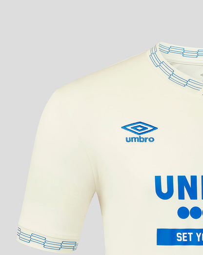 Beige sports jersey with blue accents and Umbro logo on a gray background