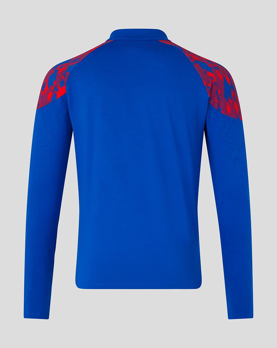A royal blue long-sleeve athletic top shown from the back, featuring red patterned shoulder panels, on a light gray background.