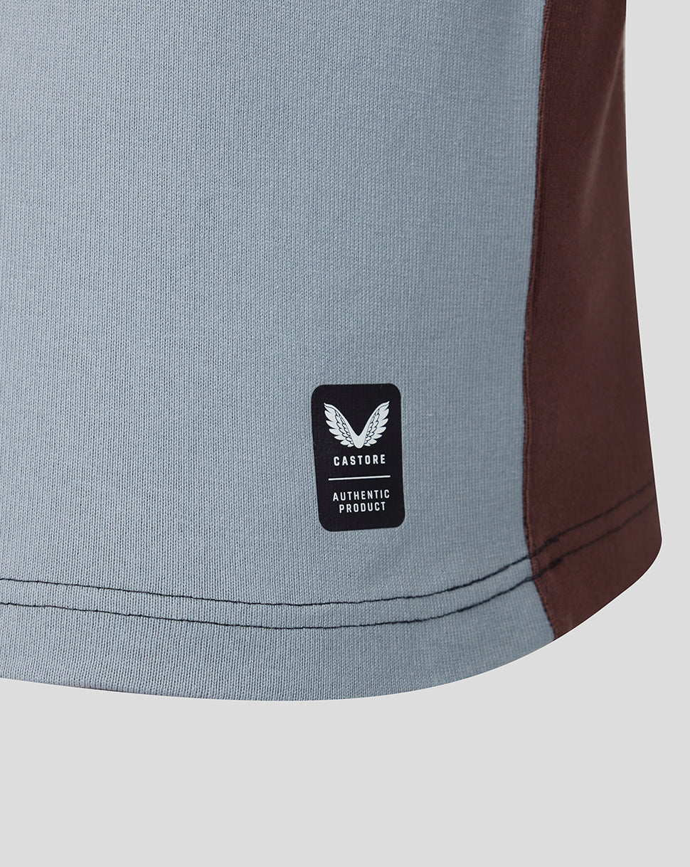 Lower hem of Harlequins home shirt with Castore authentic product patch on light blue fabric and brown side panel