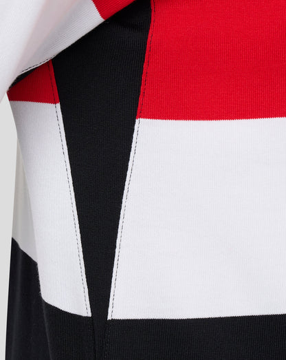 Close-up of a color-block knit garment showing bold panels of white, black, and red with visible stitching and ribbed texture.
