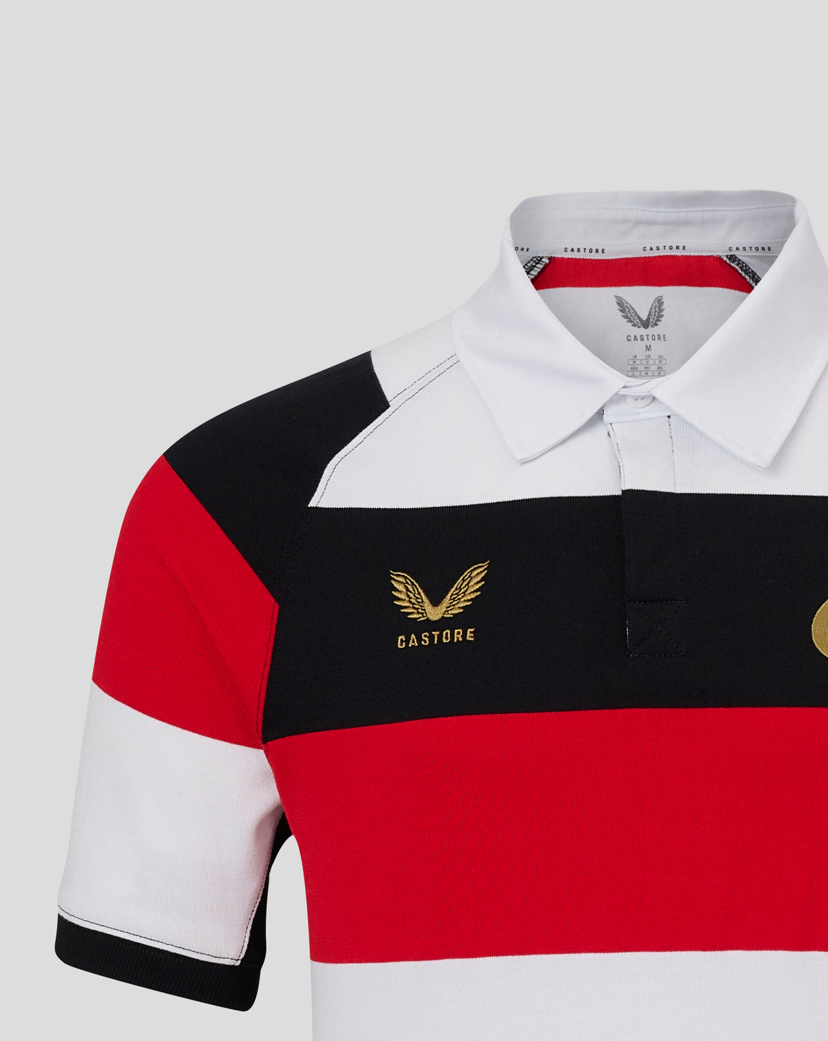 A close-up of a Castore short-sleeve polo shirt featuring horizontal color-blocked stripes of white, black, and red, with a gold winged logo on the chest.