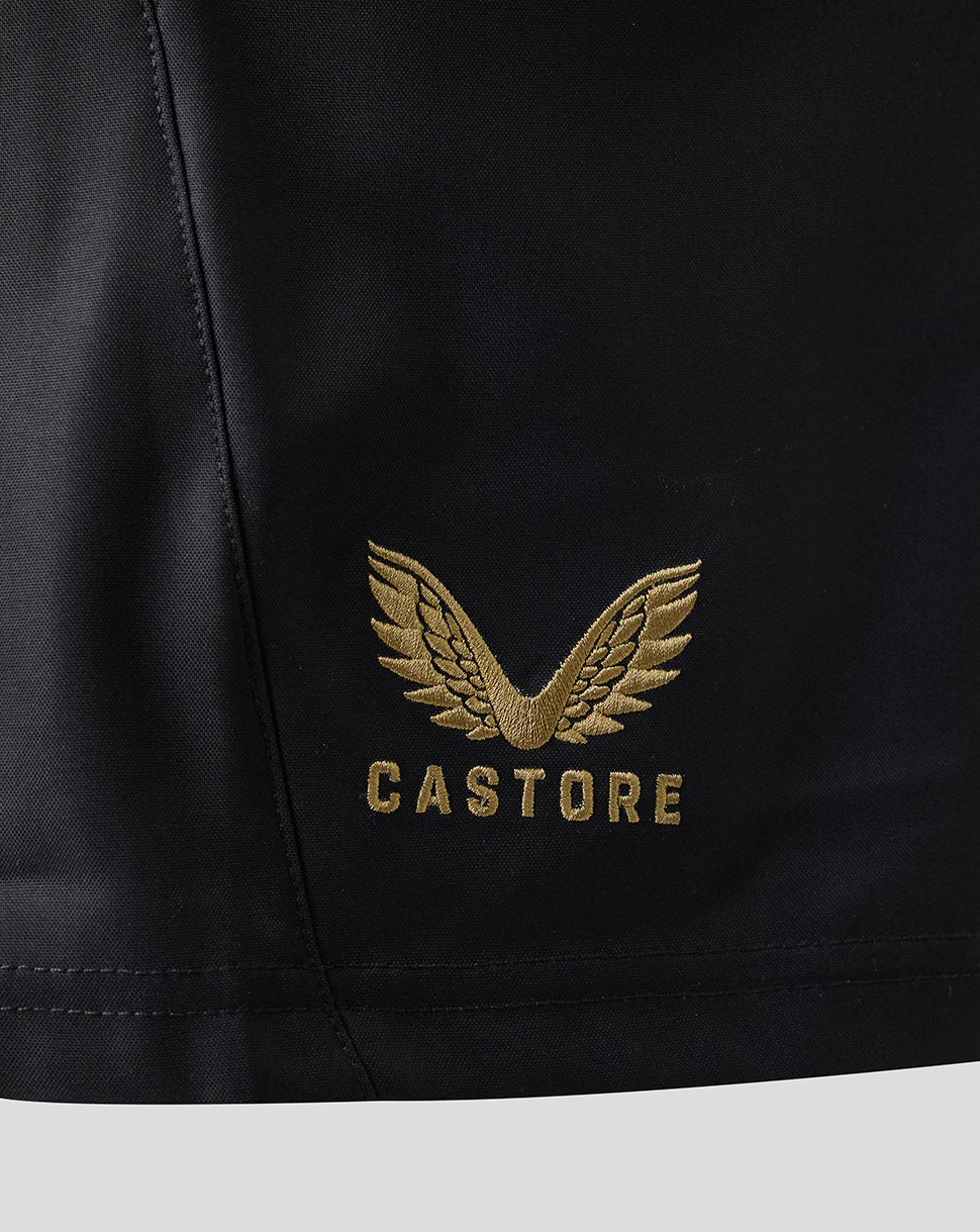 Close-up of a black garment with a gold embroidered winged logo and the word CASTORE below it, shown against a light gray background.