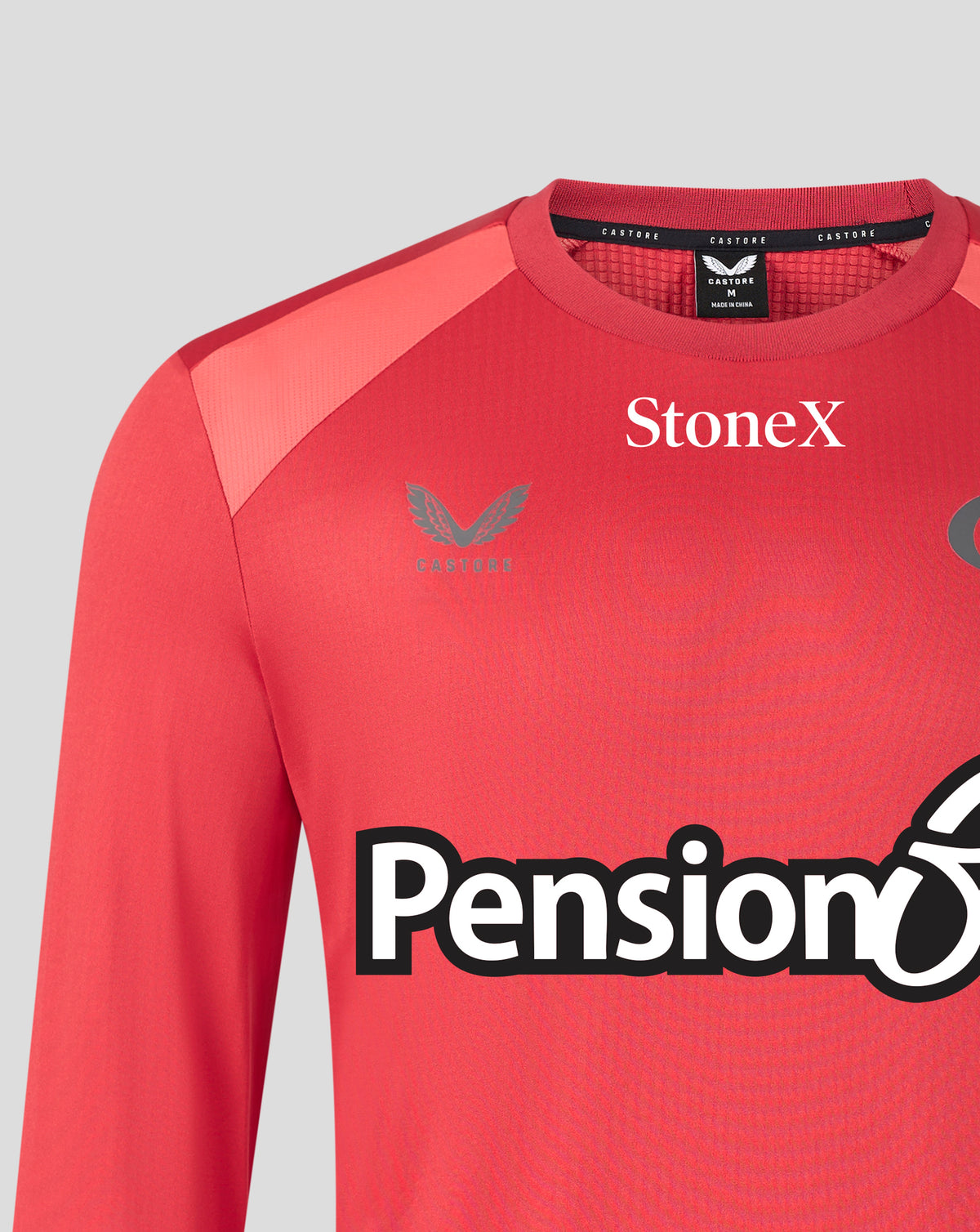 A close-up of a red long-sleeve athletic jersey with 'StoneX' printed in white on the chest and a large 'Pension' sponsor logo across the front. The brand Hummel logo is visible on the left chest.
