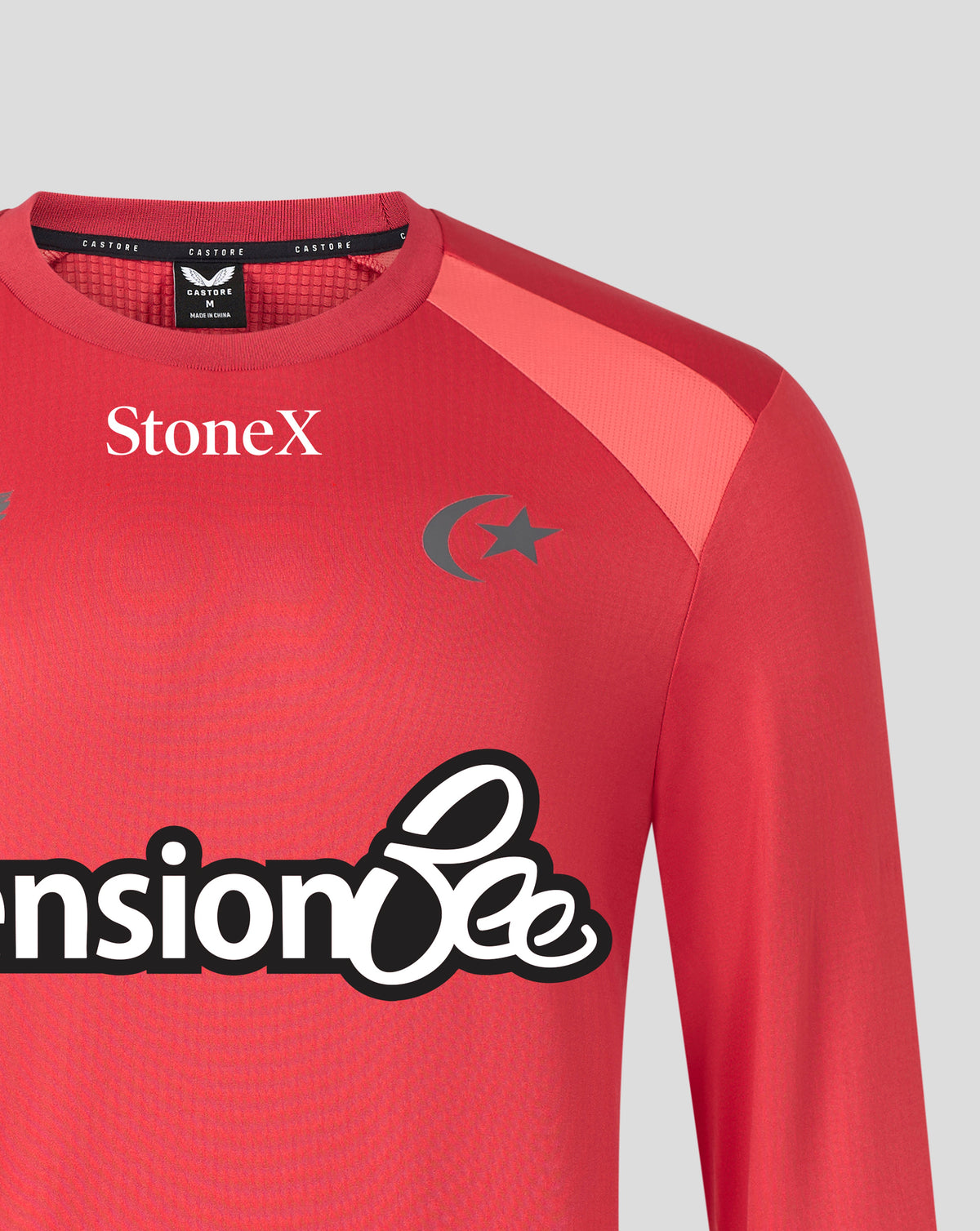 A close-up of a red long-sleeve athletic jersey with 'StoneX' printed on the chest, a dark gray crescent and star logo, and a visible neck label for 'Castore'.