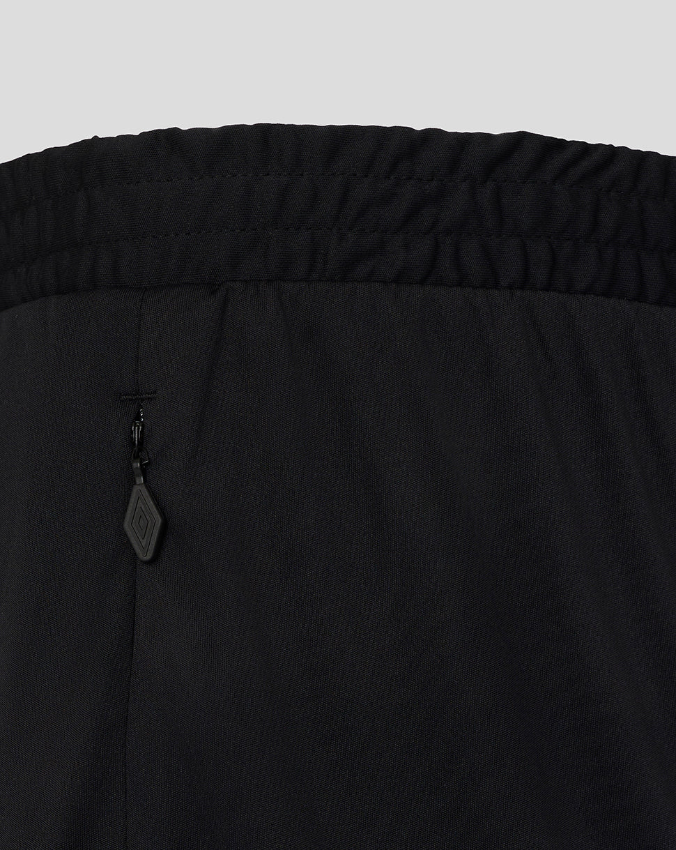 Close-up of black pants with a brand tag on a light gray background