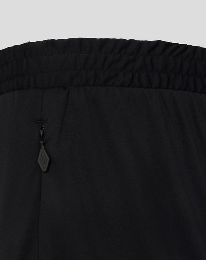 Close-up of black pants with a brand tag on a light gray background