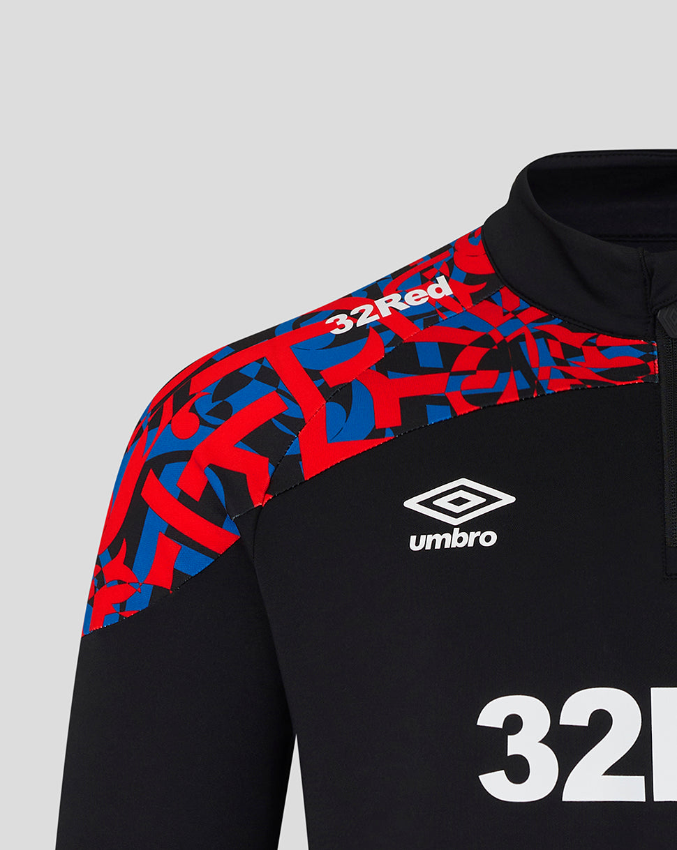 Close-up of a black athletic quarter-zip top with a red and blue geometric pattern across the right shoulder and upper chest, plus a white Umbro logo and the number 32.