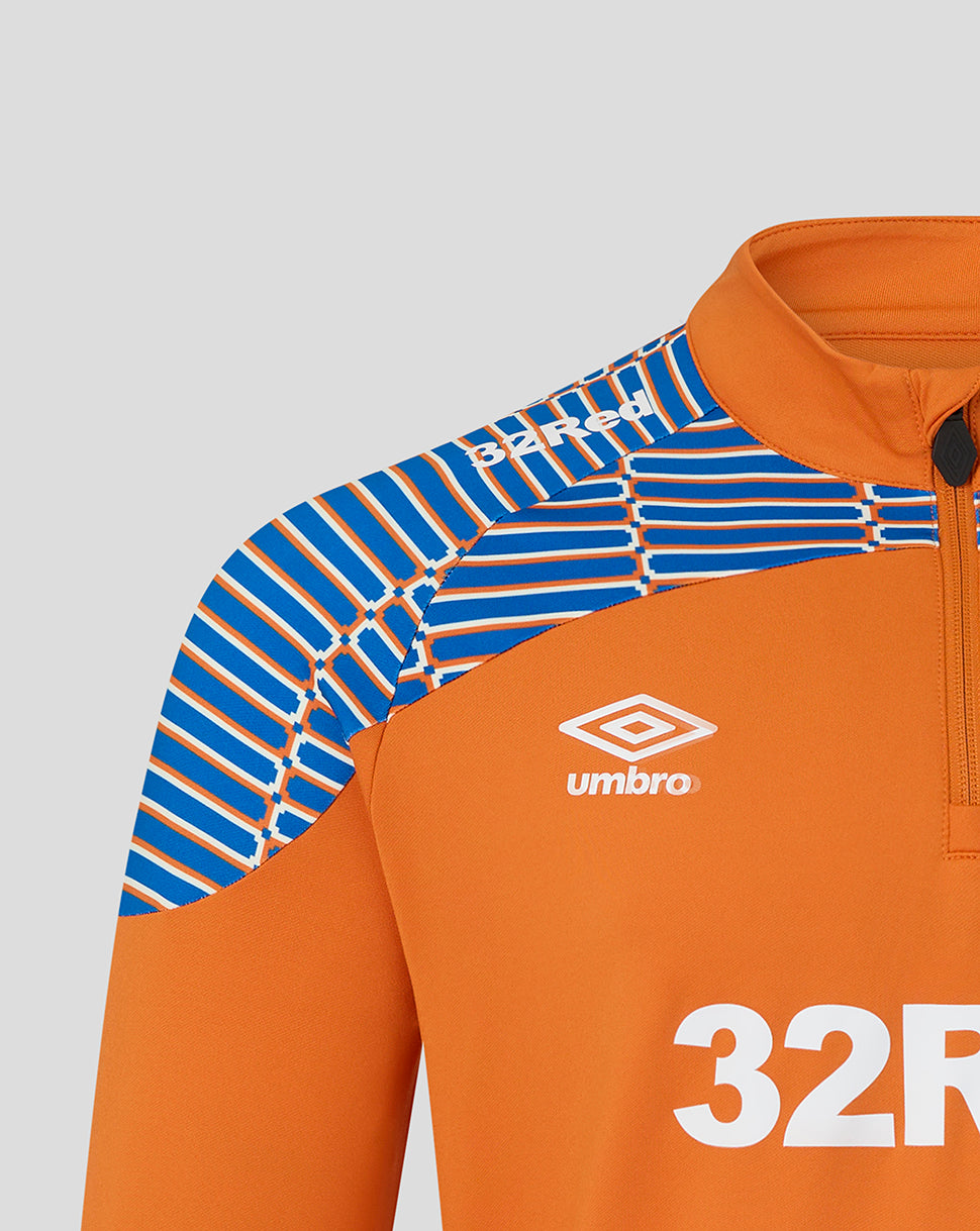 Close-up of an orange athletic quarter-zip top with a blue and white striped patterned shoulder panel and a white Umbro logo on the chest.