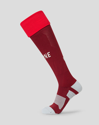 A single athletic knee-high sock in dark red with a bright red cuff, white text reading 'PNE' on the side, and white striped cushioning on the heel and toe, shown on a light gray background.