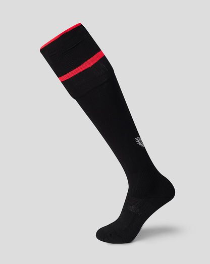 A single black knee-high athletic sock with a red band near the cuff and a small white logo on the lower leg, shown on a light gray background.