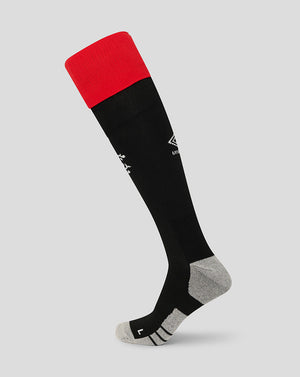 Black knee-high sock with red top on a light gray background