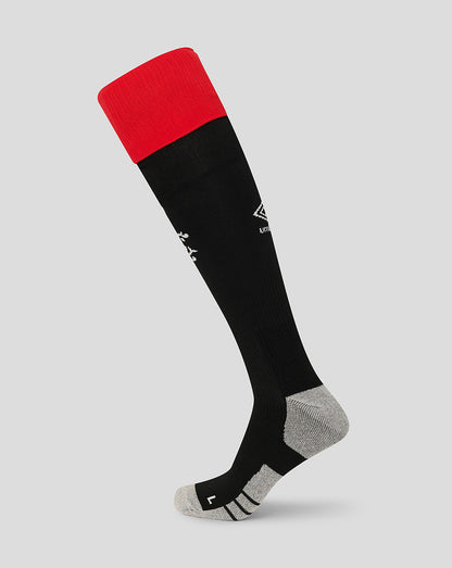 Black knee-high sock with red top on a light gray background