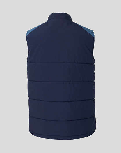 A sleeveless quilted puffer vest shown from the back, featuring a dark navy blue body with contrasting light blue shoulder panels, set against a solid light gray background.