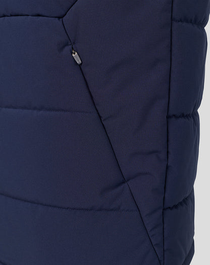 Close-up of a navy blue puffer vest showing the quilted texture, diagonal seam, and a small silver zipper pull.