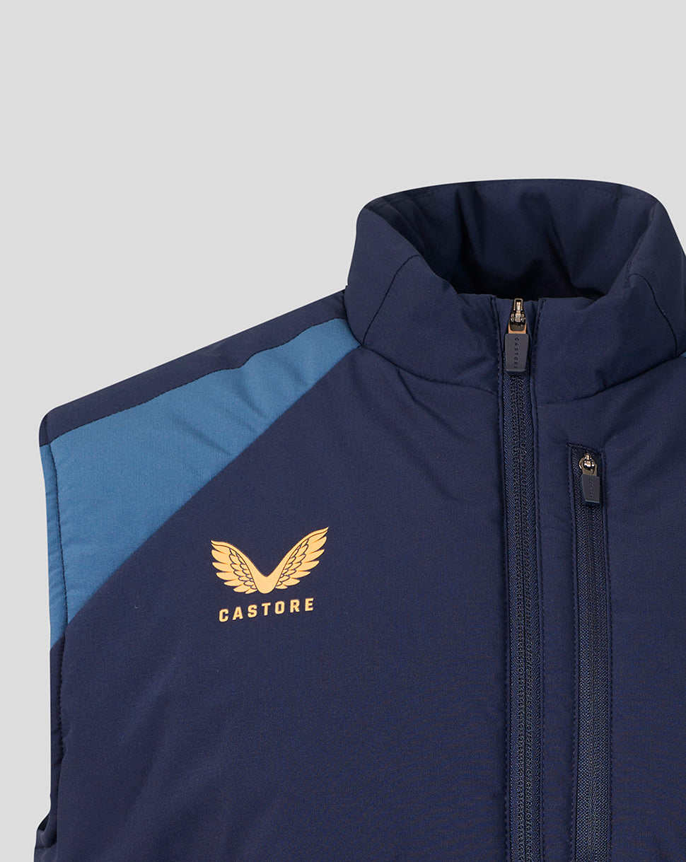 Close-up of a navy blue zip-up jacket with a light blue shoulder panel and a gold Castore wing logo on the chest, shown against a light gray background.