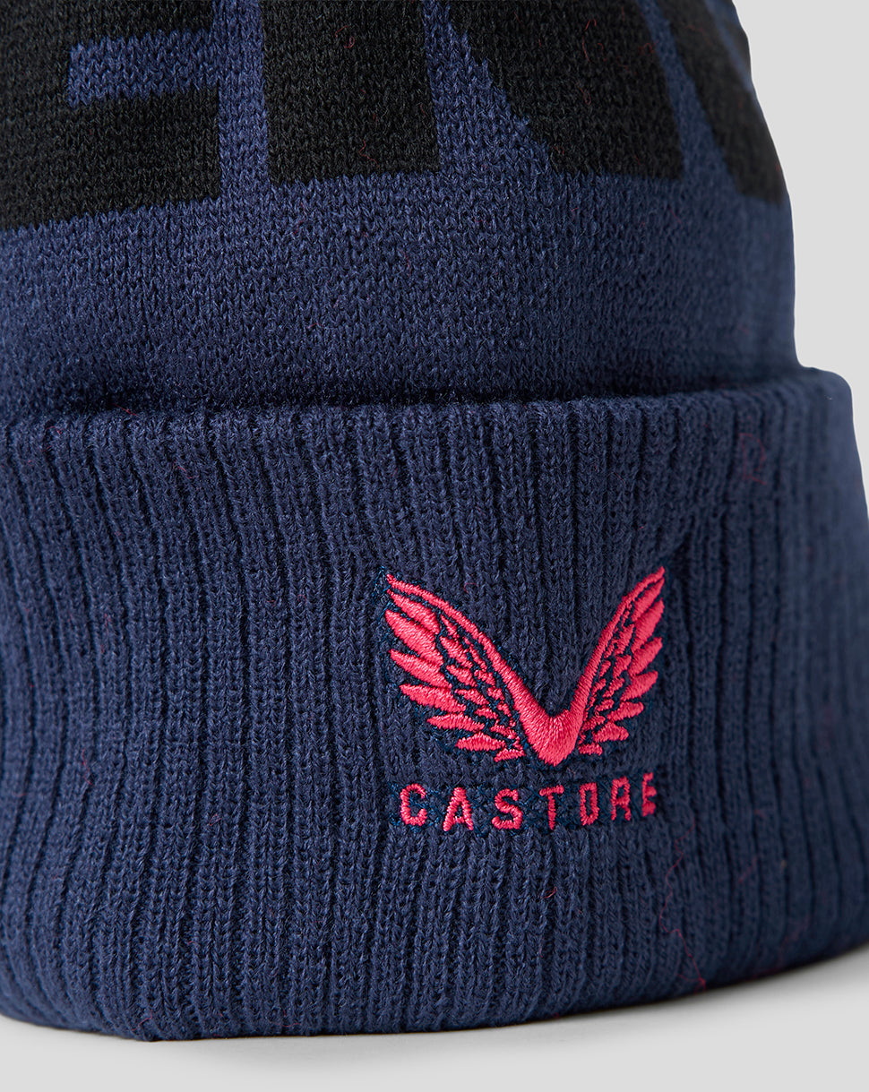 Navy blue beanie with pink wings and 'Castore' logo on a light gray background