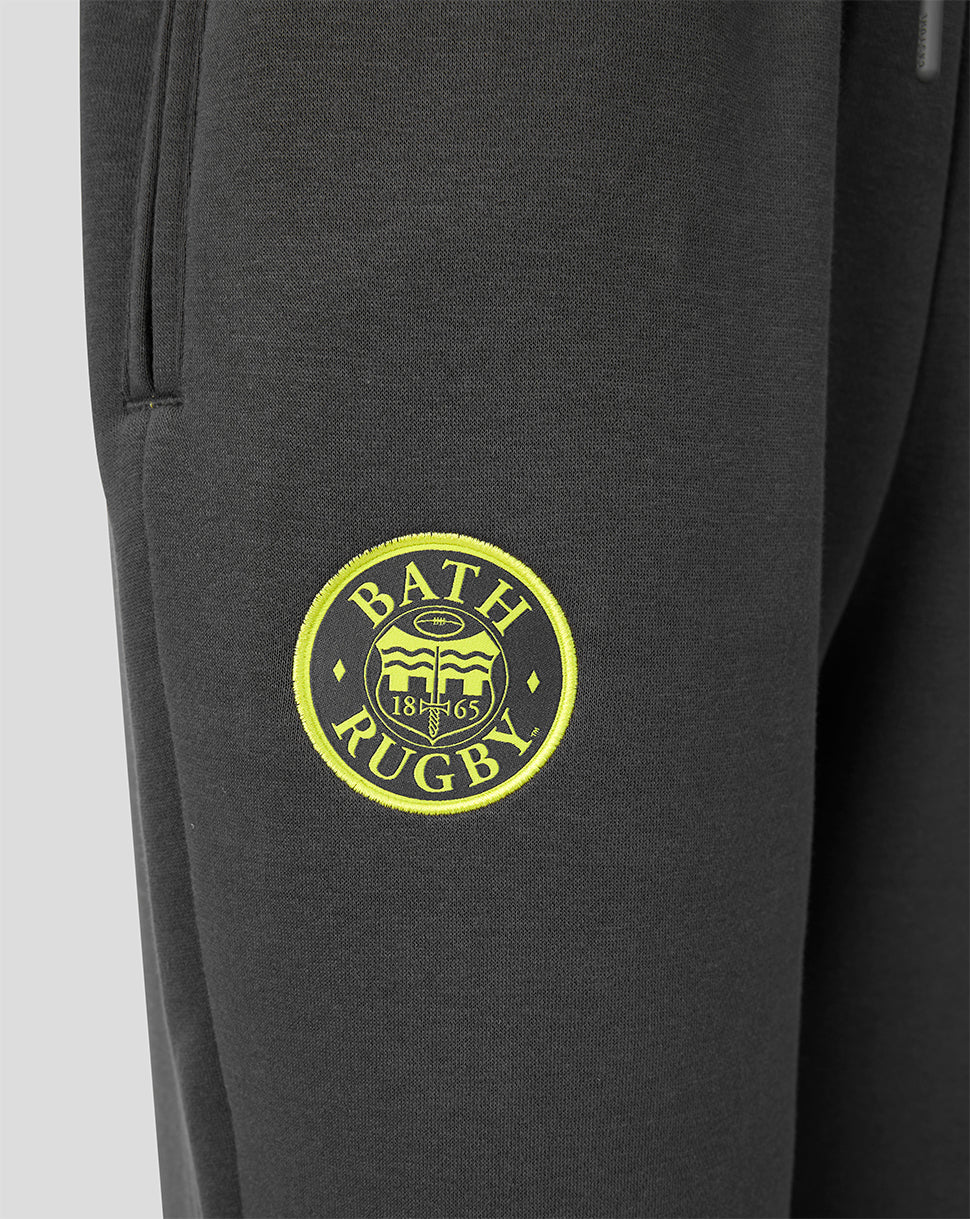 Close-up of dark gray sweatpants featuring a circular yellow and white 'Bath Rugby' logo printed on the upper thigh.