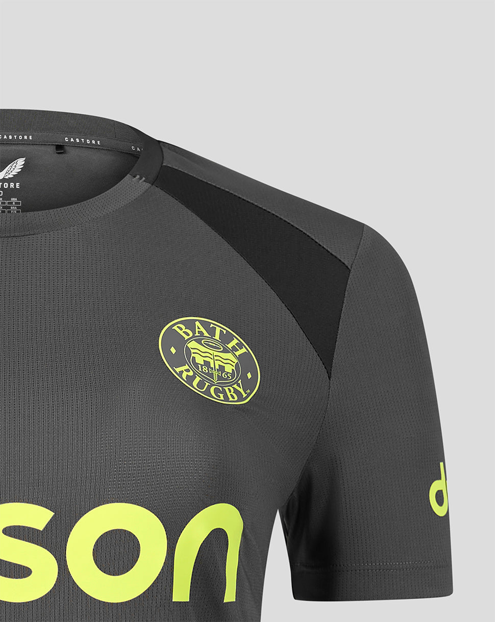 Close-up of a dark gray athletic jersey with black shoulder panels, a yellow-green Bath Rugby crest on the chest, and large neon yellow-green lettering on the front, shown against a light gray background.