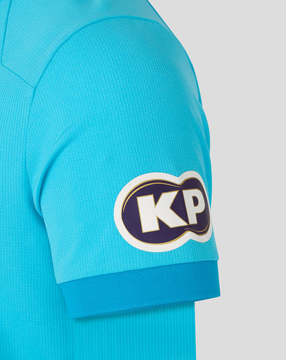 Close-up of a turquoise sports jersey with a logo on the sleeve against a light gray background