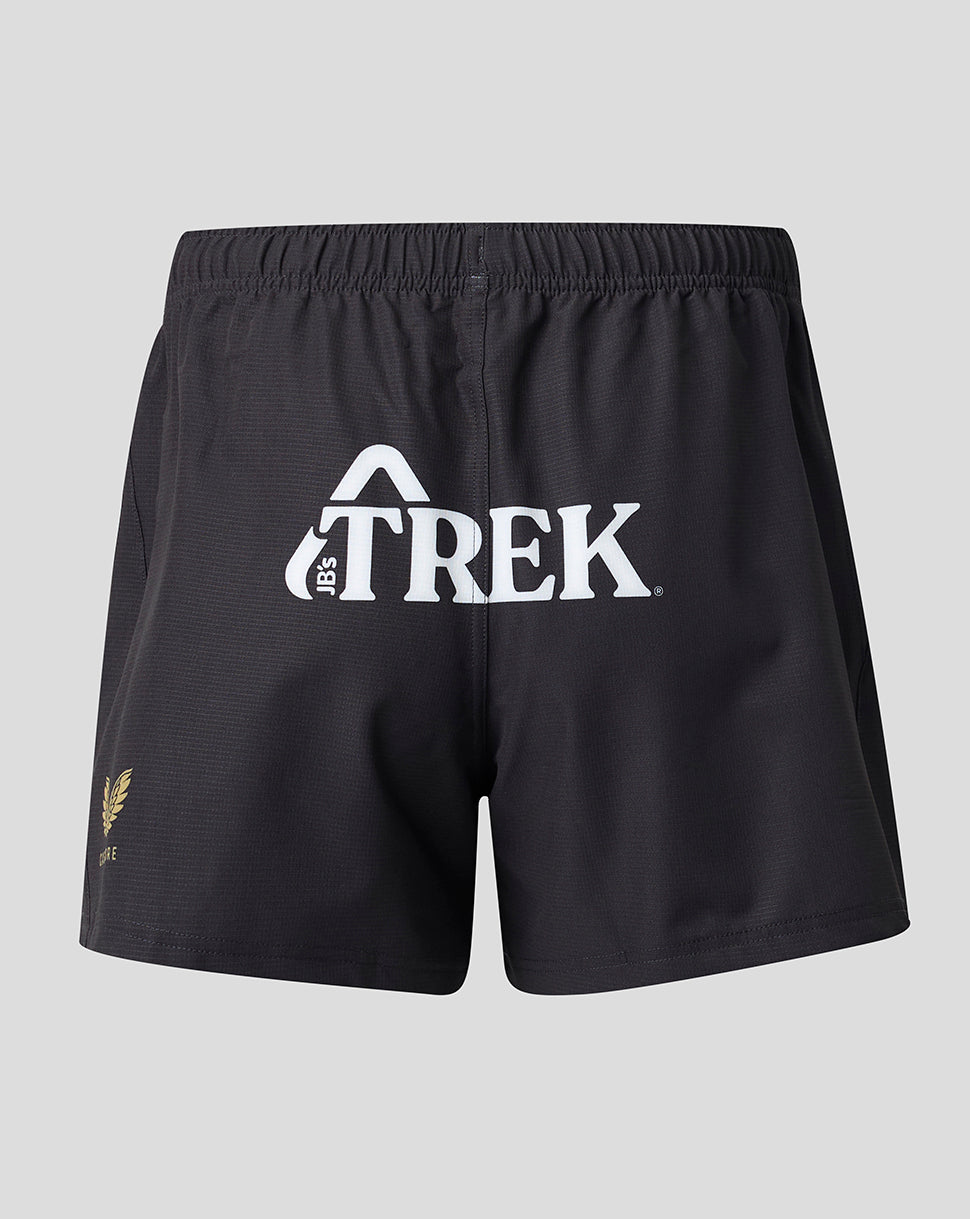 Black athletic shorts with a white 'TREK' logo on the front and a small gold fern logo on the lower left leg, shown against a light gray background.