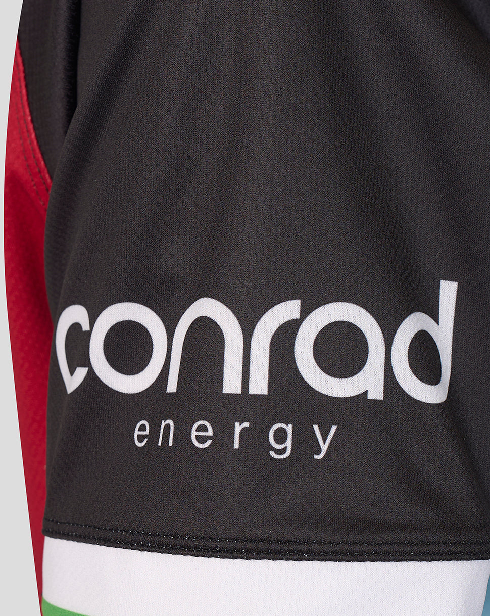 Close-up of a black athletic jersey with a large white 'conrad energy' logo on the front, showing a sliver of red and white side panels.