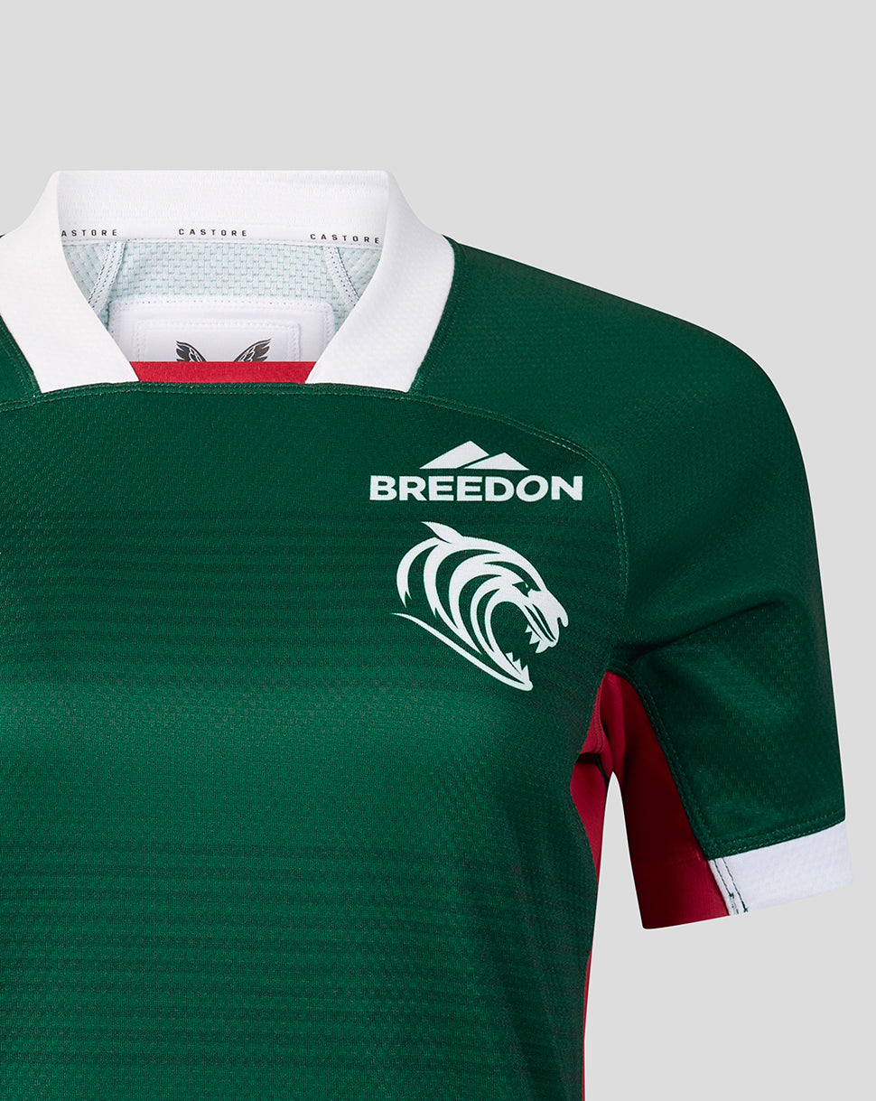 Close-up of a dark green rugby jersey with a white collar, white 'BREEDON' text and lion logo on the chest, and burgundy side panels, shown on a light gray background.