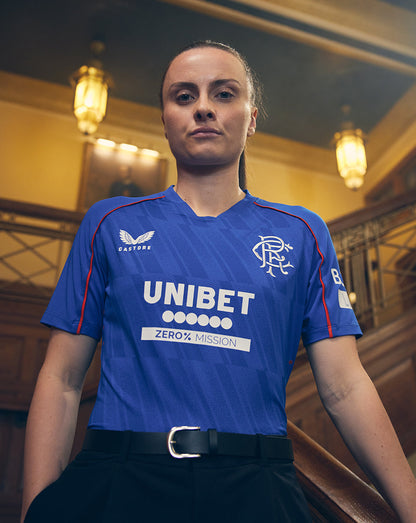 Model wearing blue Rangers Women’s 24/25 Home Shirt showing V neck collar and raglan sleeves with UNIBET sponsor