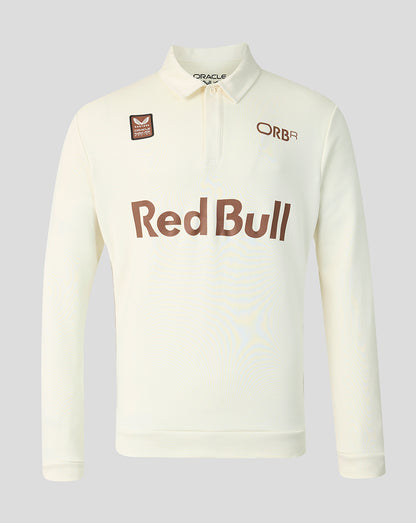 An off-white long-sleeve polo shirt with a brown 'Red Bull' logo across the chest, an 'ORB' logo on the right chest, and a small sponsor patch on the left chest, shown on a neutral gray background.