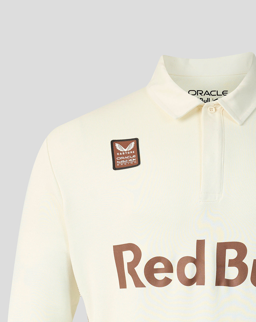 Close-up of a cream-colored long-sleeve polo shirt with a brown 'Red Bull' sponsor logo on the front and a matching brown patch on the chest. The inner collar shows 'ORACLE' branding.