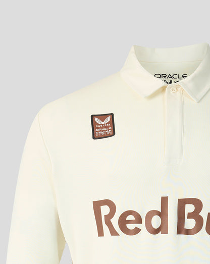 Close-up of a cream-colored long-sleeve polo shirt with a brown 'Red Bull' sponsor logo on the front and a matching brown patch on the chest. The inner collar shows 'ORACLE' branding.