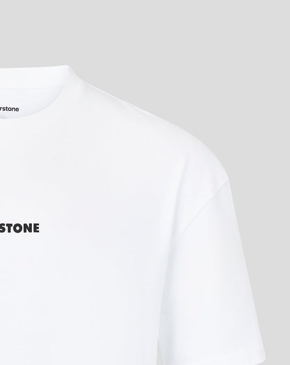 Close-up of a white short-sleeve T-shirt showing the left chest area with partial black 'SILVERSTONE' text and a small black brand mark inside the collar on a light gray background.