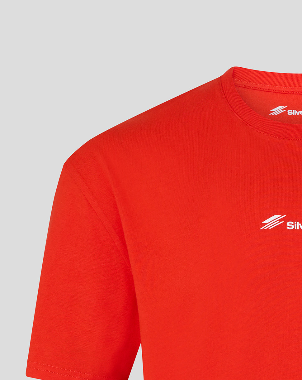 Close-up of a bright red short-sleeve t-shirt showing the left chest area with a small white logo and the inner neck label.