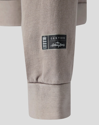 Close-up of a light taupe sweatshirt sleeve featuring a black rectangular Castore logo patch on the upper cuff.