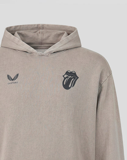 A close-up of a light taupe-beige hooded sweatshirt featuring a black Rolling Stones tongue-and-lips logo on the left chest and a black winged logo with 'CASTORE' text on the right chest.