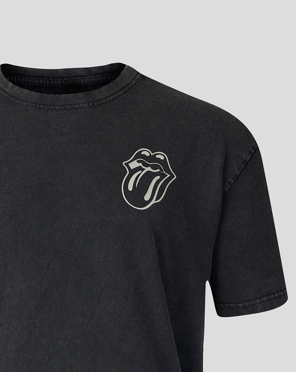 A close-up of a dark gray washed t-shirt featuring the white embroidered Rolling Stones tongue and lips logo on the left chest, set against a solid light gray background.