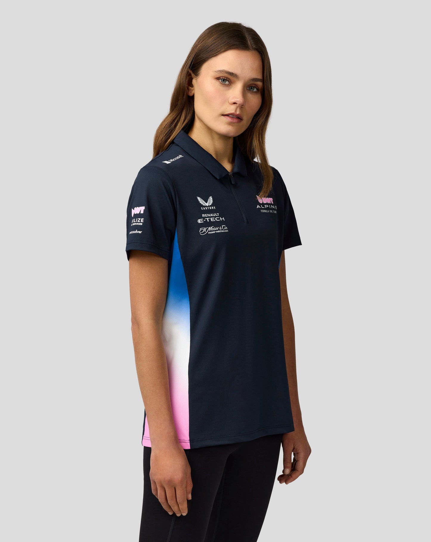 Portrait of a woman in a navy BWT Alpine polo with visible team logos on the chest and collar