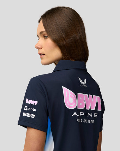Profile view of a woman wearing a navy BWT Alpine Team polo with a white crest on the back and pink branding