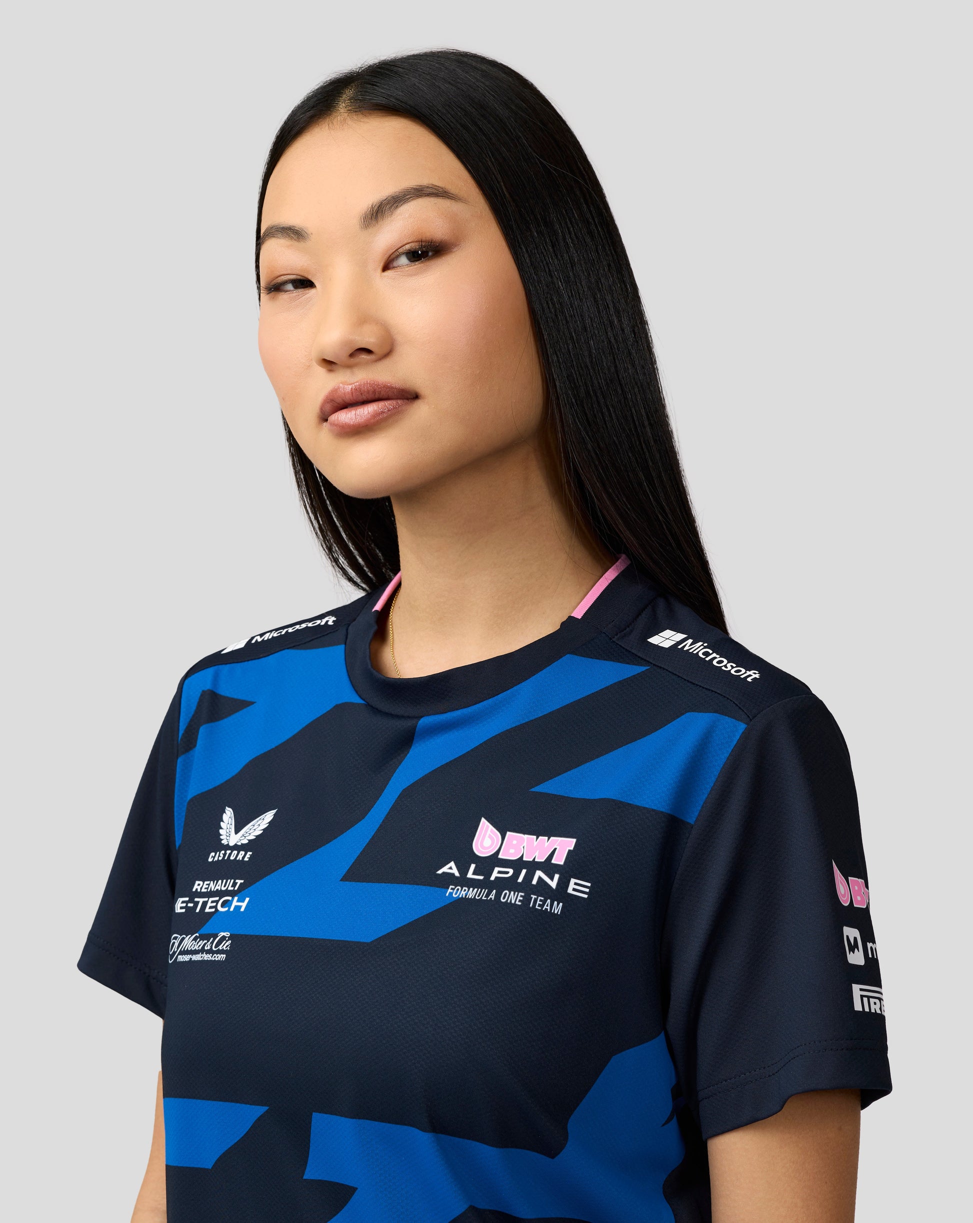 Close up of model wearing navy BWT Alpine driver jersey with sponsor logos on shoulder and pink neckline trim.
