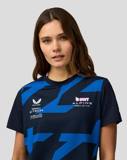 Portrait of a woman wearing a navy Alpine Formula One Team jersey with blue geometric patterns and sponsor logos.
