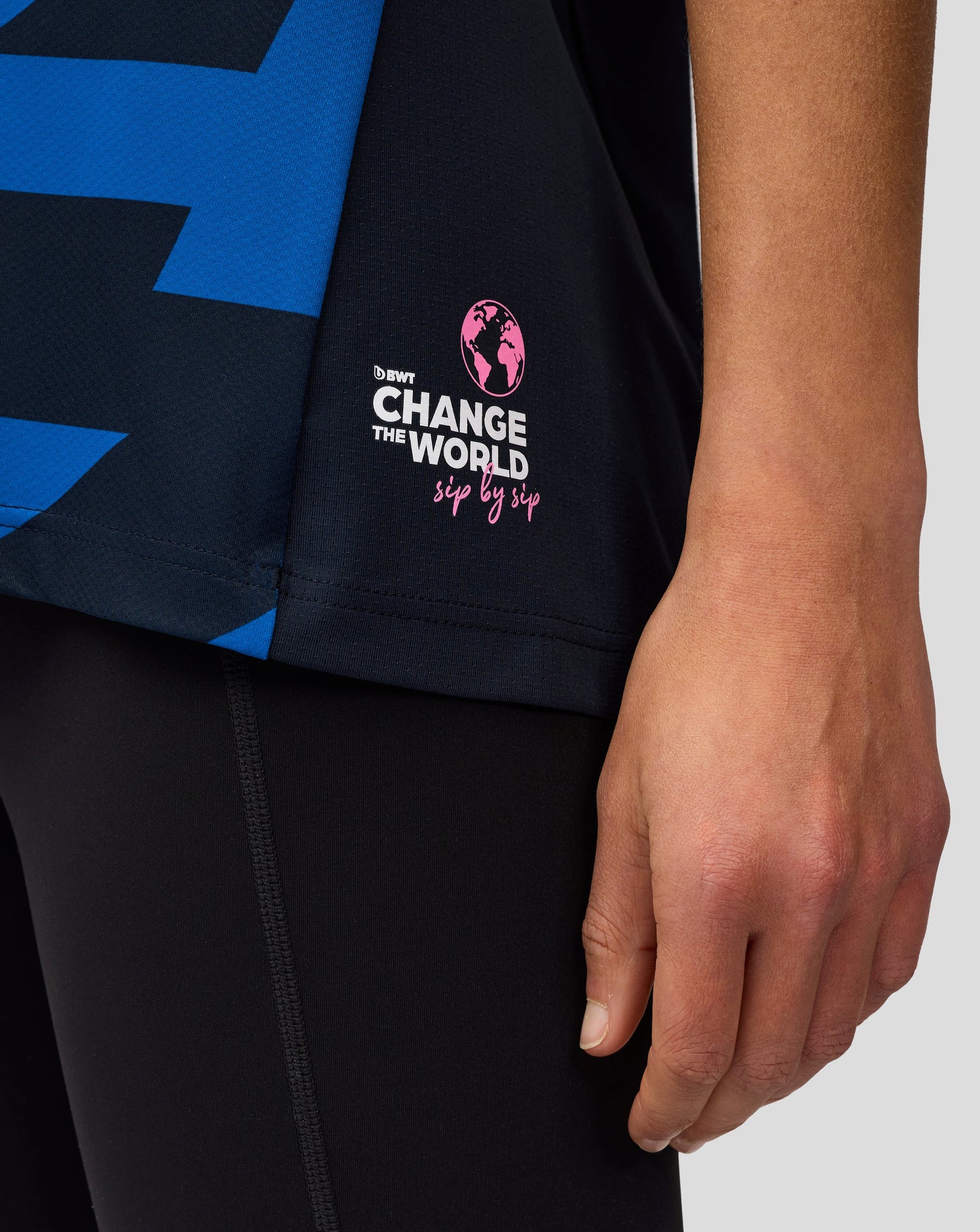 Close up of a navy jersey sleeve showing a pink globe logo and the Change the World sip by sip slogan.