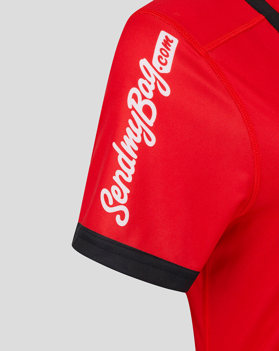 Close-up of red jersey sleeve showing white script text and black cuff trim.