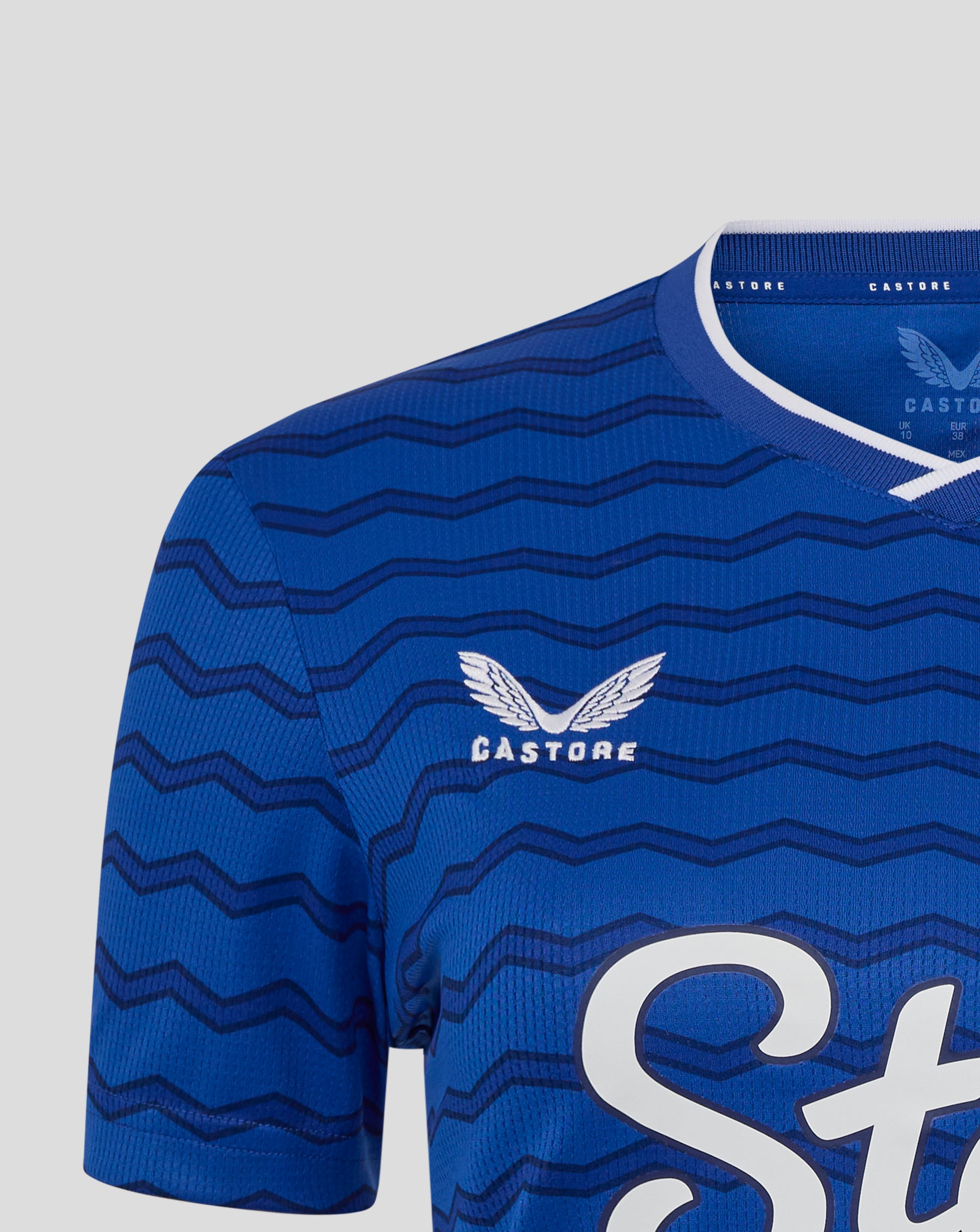 Close up of blue Everton FC women's home shirt with wavy chevron pattern, white neck trim, and Castore branding.